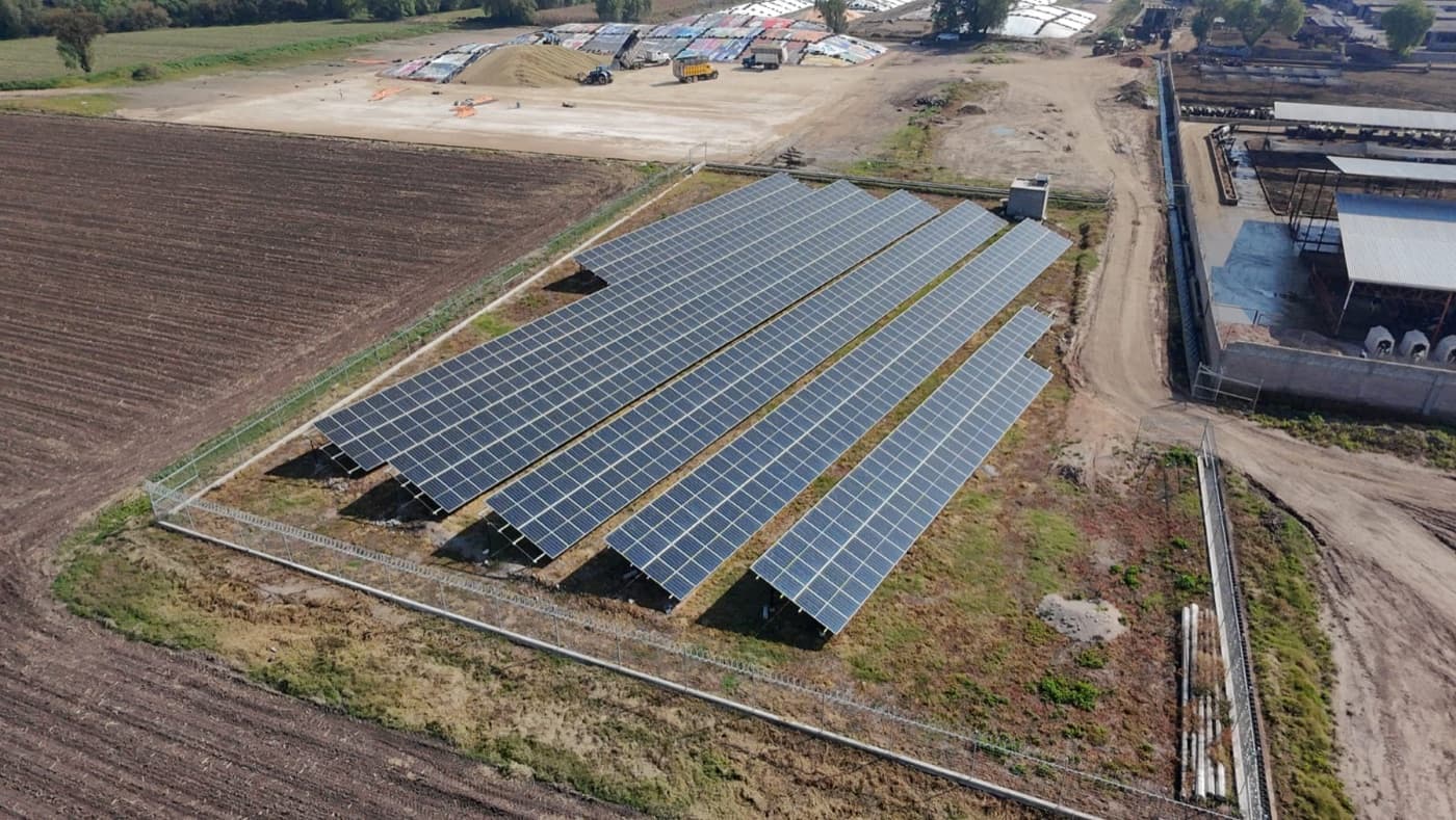 Planta solar fotovoltaica en campo junto a instalaciones agroindustriales — proyecto EYCOT