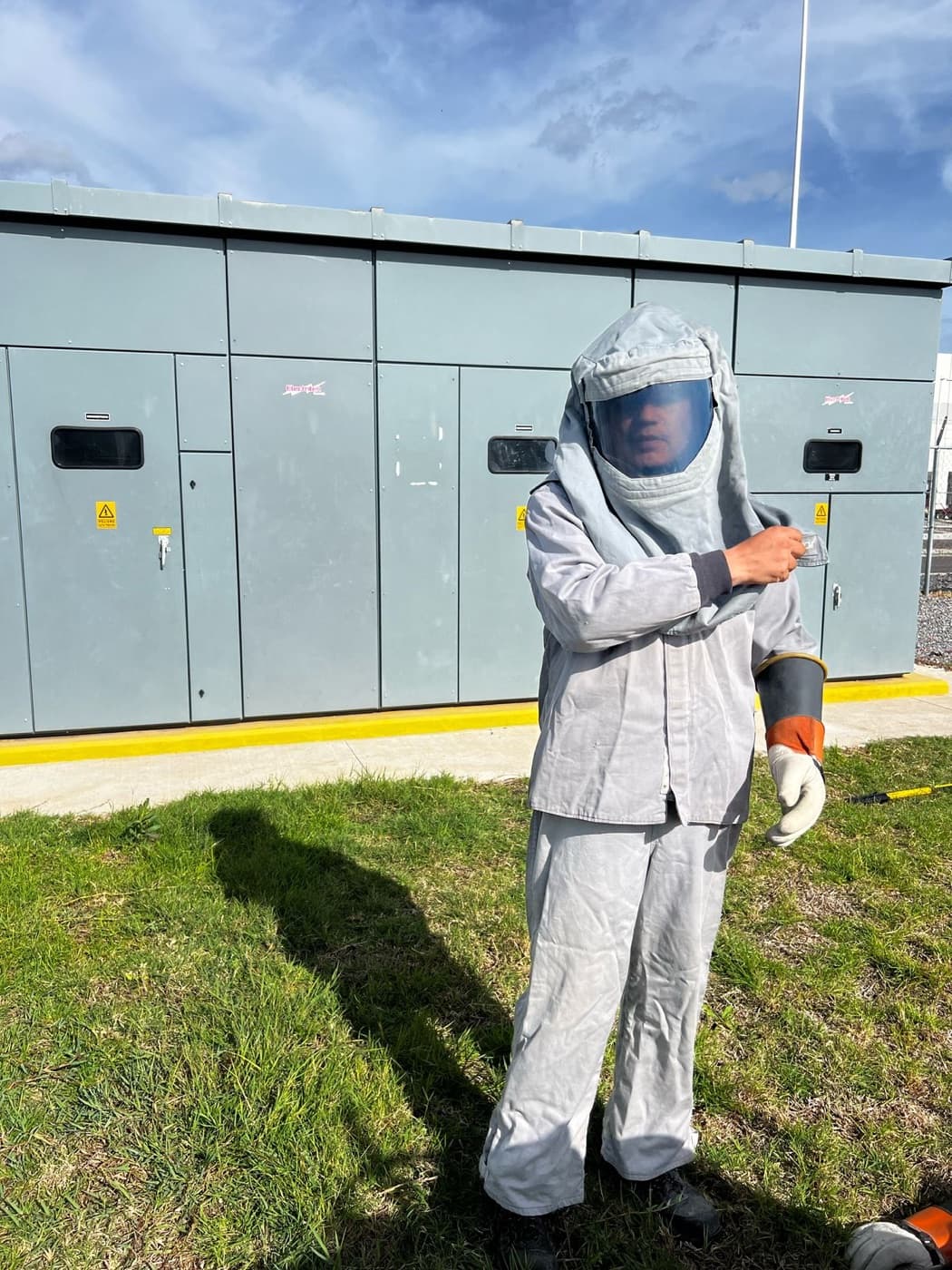 Técnico EYCOT con traje de protección contra arco eléctrico frente a tablero de media tensión